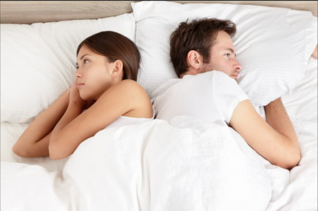 Un couple se tournant le dos dans un lit et ayant des problèmes de sexualité